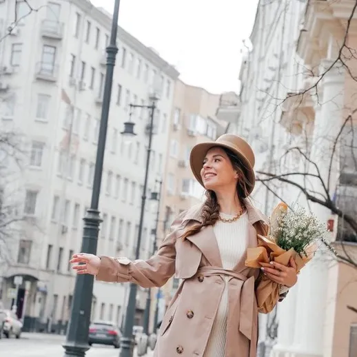 Женщина с букетом цветов идет по улице в городе в ясный день