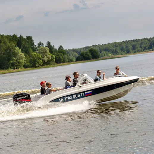 Небольшой катер с людьми на реке в летний день, наслаждающимися прогулкой по живописным просторам