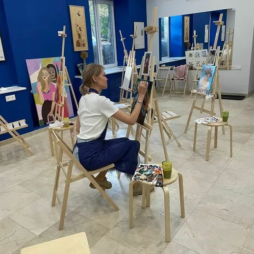 Художница рисует в студии на занятиях по живописи в современном арт-пространстве