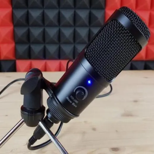 Микрофон установлен на столе в звукозаписывающей студии с красной фоновой стеной