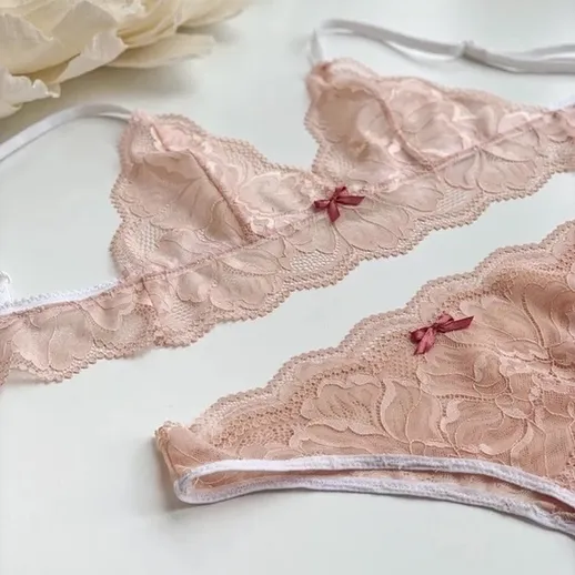 Розовое кружевное нижнее белье на белом фоне с цветами, создающее атмосферу романтики и нежности