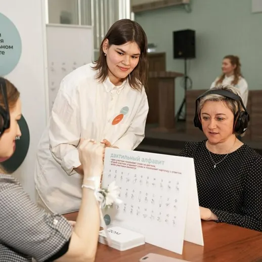 Женщина помогает другой на выставке, обучающей использованию технологий, в образовательном центре на семинаре