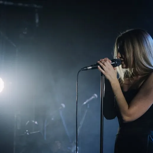 Концертная певица на сцене, погружённая в музыку, яркие огни создают атмосферу