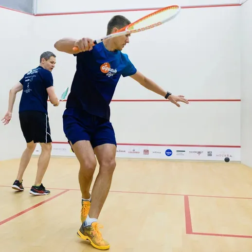 Игроки в сквош на корте. Два человека соревнуются в спортивной игре в закрытом помещении