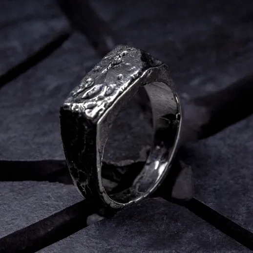 Уникальное кольцо с текстурированной поверхностью на фоне черного камня в элегантном дизайне