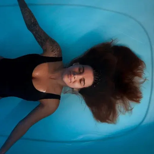 Женщина с распущенными волосами, погруженная в воду аквапарка, наслаждается спокойствием и расслаблением