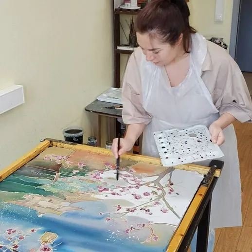 Художница рисует цветущую вишню в студии на фоне природы