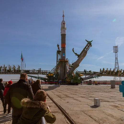 Запуск ракеты с космодрома Байконур в ясный зимний день, зрители наблюдают с площадки