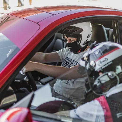 Гонки на спортивных автомобилях на трассе в солнечный день с участниками в защитной экипировке