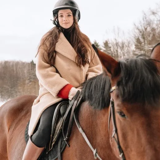 Женщина катается на лошади в зимнем лесу, окутанном снегом и тишиной