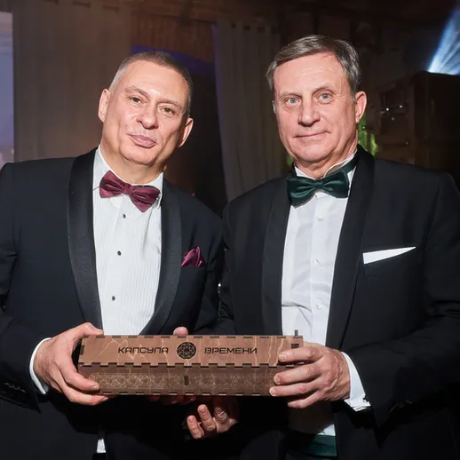 Два мужчины на торжественном мероприятии с наградой в руках в украшенном зале