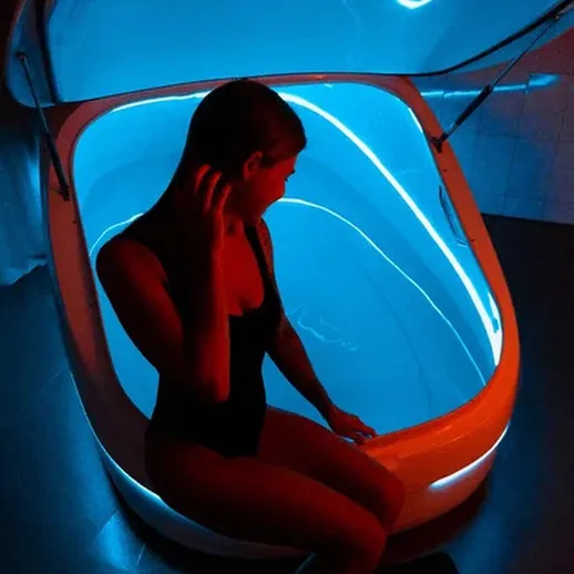 Женщина сидит в светящемся флотирующем отсеке с яркой подсветкой