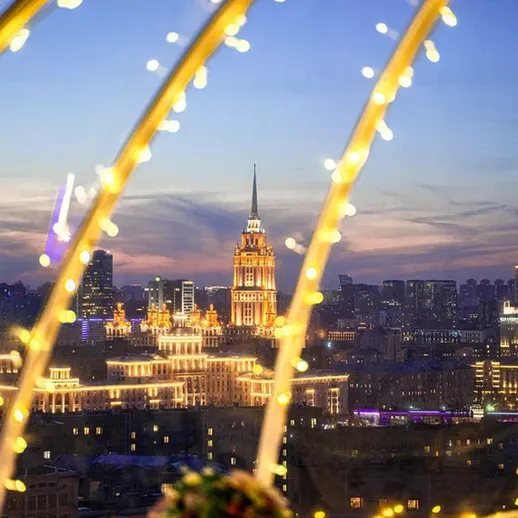 Вечерний вид на Москву с иллюминацией, освещающие площадь и здания, на фоне заката