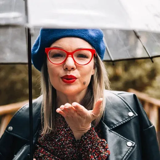 Женщина с красными очками и зонтом целует на прощание на мосту в дождливый день