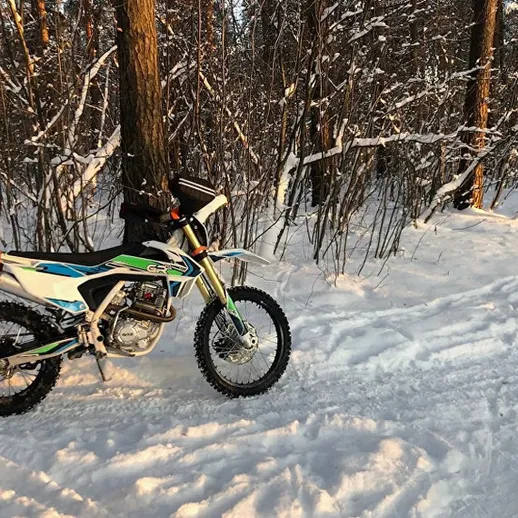 Зимняя прогулка на внедорожном мотоцикле по снежному лесному маршруту в горах