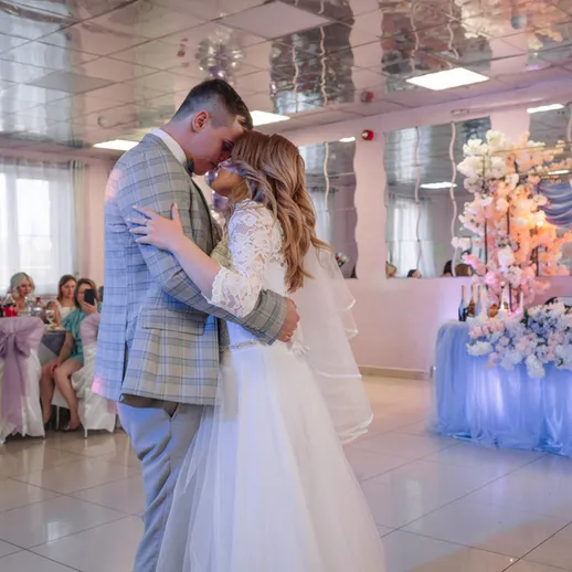 Свадебный танец молодой пары в праздничном зале с розовыми лепестками и красивым оформлением