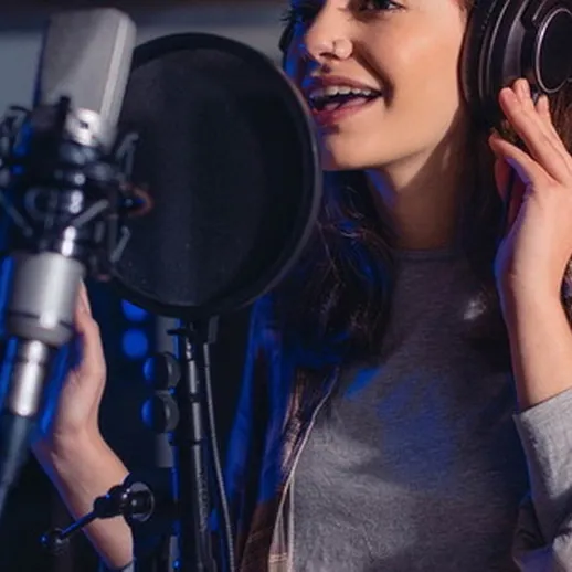 Молодая певица записывает вокал в студии звукозаписи, окруженная профессиональным оборудованием и мягким светом