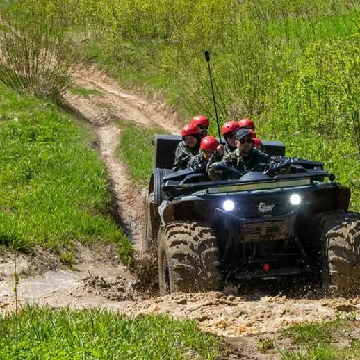 Внедорожник проезжает по грязной дороге в лесу с туристами в касках в солнечный день