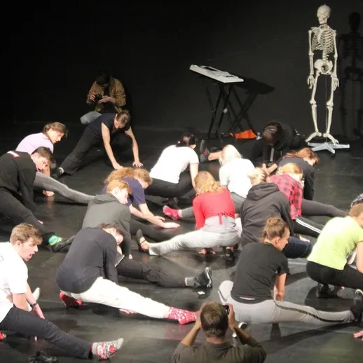 В группе танцоров в Черном зале проходят занятия по растяжке с использованием скелета для наглядности