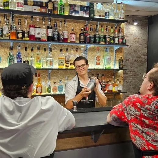 Бармен обслуживает клиентов в уютном баре с большим выбором спиртных напитков