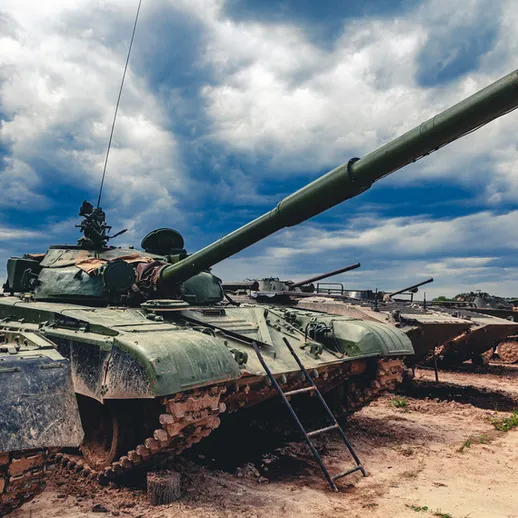 Танки стоят на военной базе в открытой местности под облачным небом