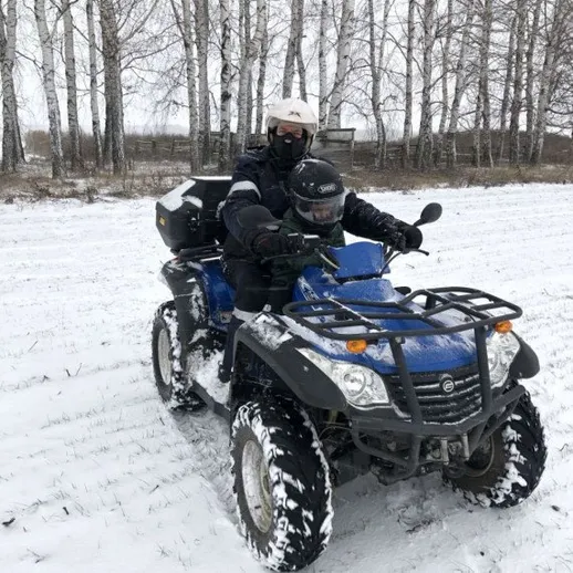 Мужчина на квадроцикле едет по снежному полю в зимний день