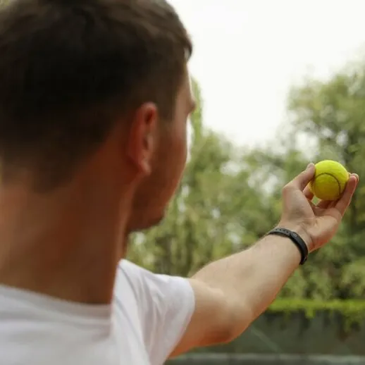 Молодой теннисист готовится к подаче на корте в ясный день