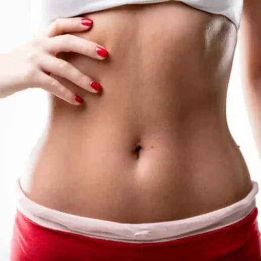 Девушка с привлекательной фигурой позирует в светлой одежде и красных ногтях, показывая свою талию и уверенность в себе