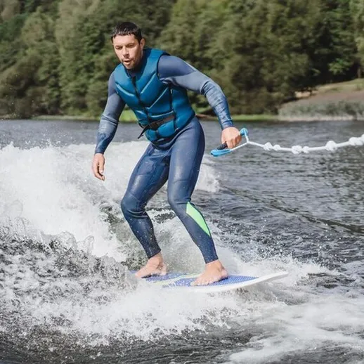 Серфинг на воде в живописном месте, человек в гидрокостюме наслаждается катанием на доске