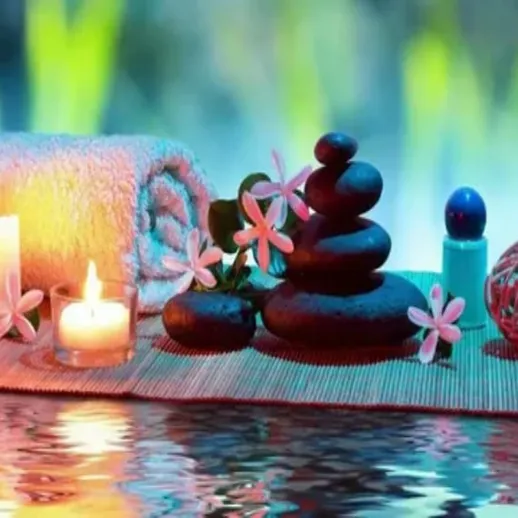 Спокойная атмосфера спа-салона с камнями, свечами и цветами на столике у воды в вечернее время