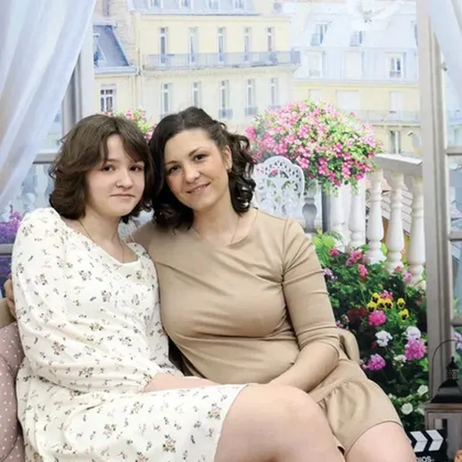 Две женщины отдыхают на диване в уютном помещении с декором, напоминающим Париж, в солнечное время дня