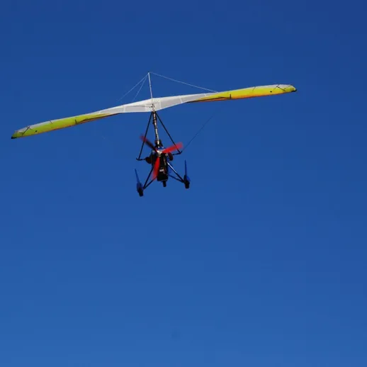 Парапланерист осуществляет полет над ясным небом в солнечный день, наслаждаясь свободой и красотой природы