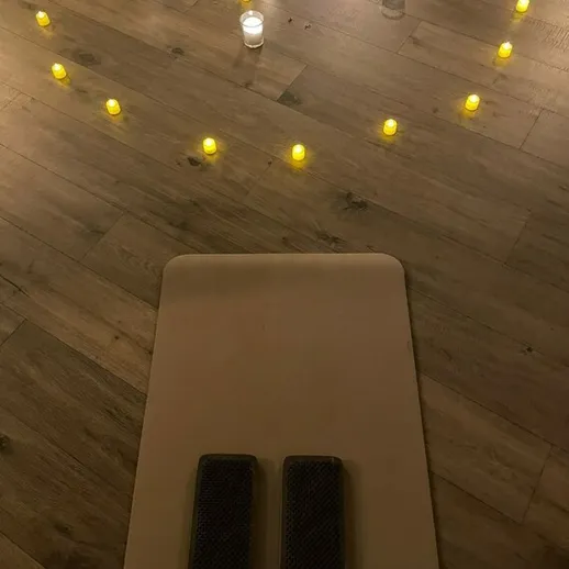 Уютное место для медитации с десятками свечей на деревянном полу в вечернее время