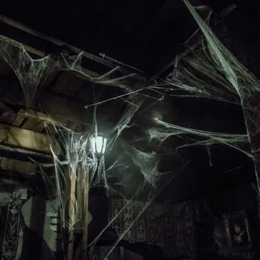 Мистическая атмосфера заброшенного помещения с паутиной и тусклым светом фонаря