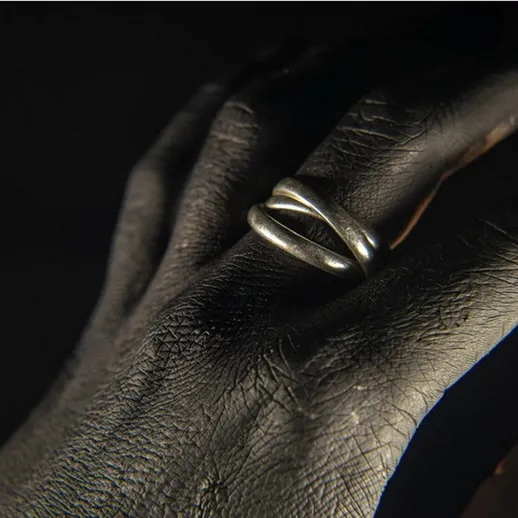 Крупный план руки с серебряным кольцом под мягким светом в темном помещении, показывающем текстуру кожи и украшения