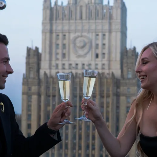 Пара наслаждается бокалом шампанского на фоне городской архитектуры в вечернее время