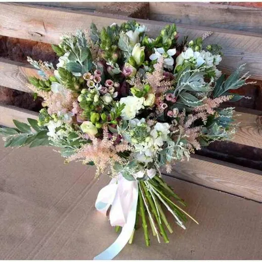 Букет из цветов, составленный из белых и зелёных растений на деревянном фоне