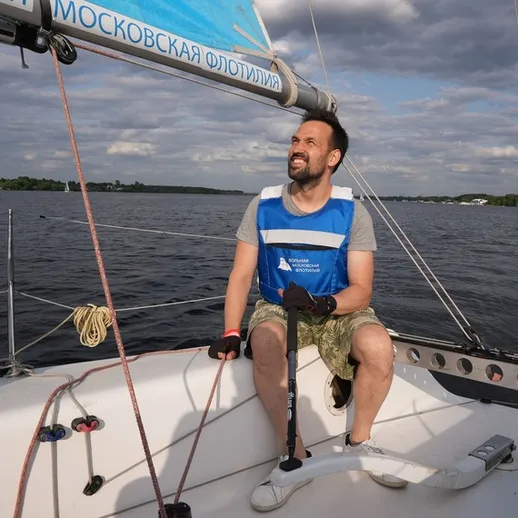 Мужчина управляет парусной лодкой на московском водоеме в ясный день