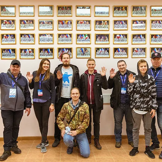 Участники мероприятия позируют на фоне стены с фотографиями в помещении в России