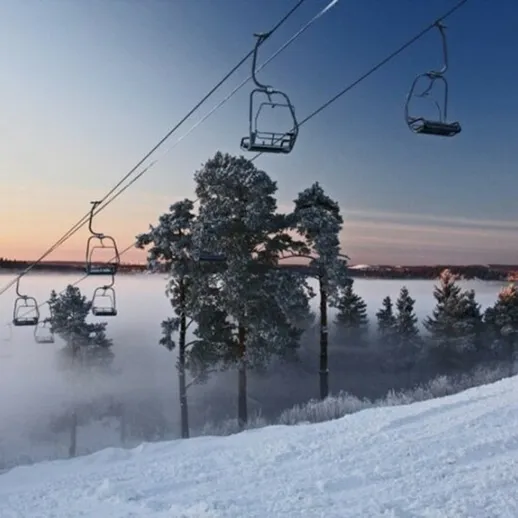 Канатная дорога на фоне зимнего леса и тумана в предзакатные часы