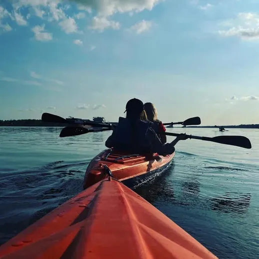 Пара на каяках наслаждается спокойной водой реки под ясным небом в теплый день