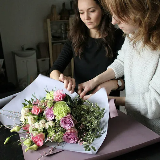 Женщины собирают красивый букет цветов в уютном помещении с натуральным освещением