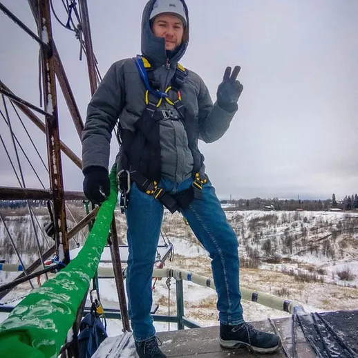 Мужчина в защитной экипировке выполняет работу на высоте в зимний день в снежном пейзаже