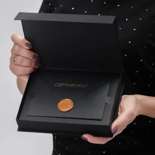 Кто-то держит черный сертификат с золотой печатью в руках