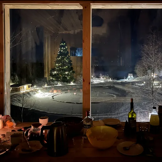 Зимний вечер с уютным интерьером и новогодней елкой за окном в загородном доме