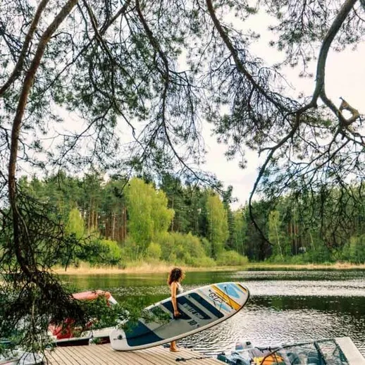 Молодая девушка готовится выйти на воду с каяком на спокойном озере в летний день