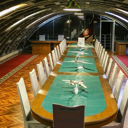 Подземный конференц-зал с длинным столом и миниатюрами самолетов в старом бункере