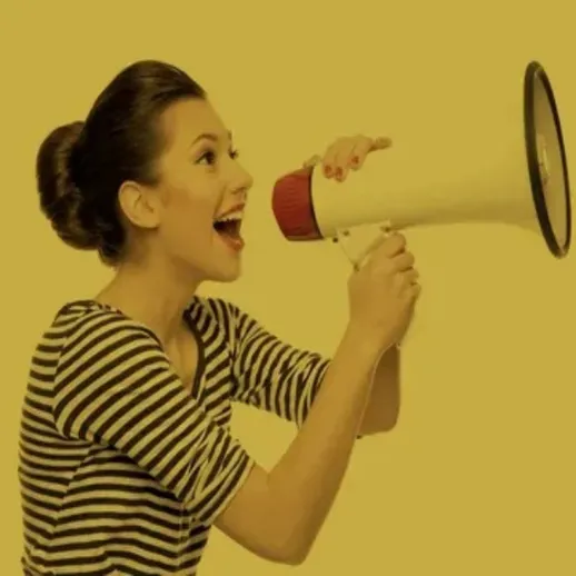 Девушка в полосатом свитере громко говорит в мегафон на желтом фоне, выражая радость и энергию