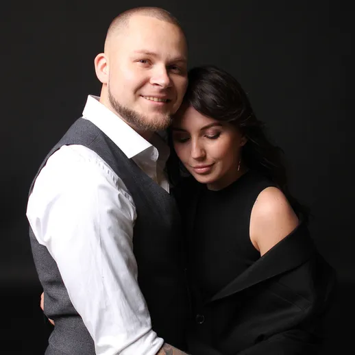 Парочка обнимается на черном фоне, демонстрируя близость и любовь в уютной обстановке