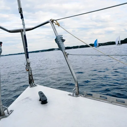 Парусная лодка на озере в ясный день с облаками, вдали видны другие яхты